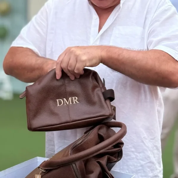 hombre abriendo un regalo de un neceser de piel con iniciales